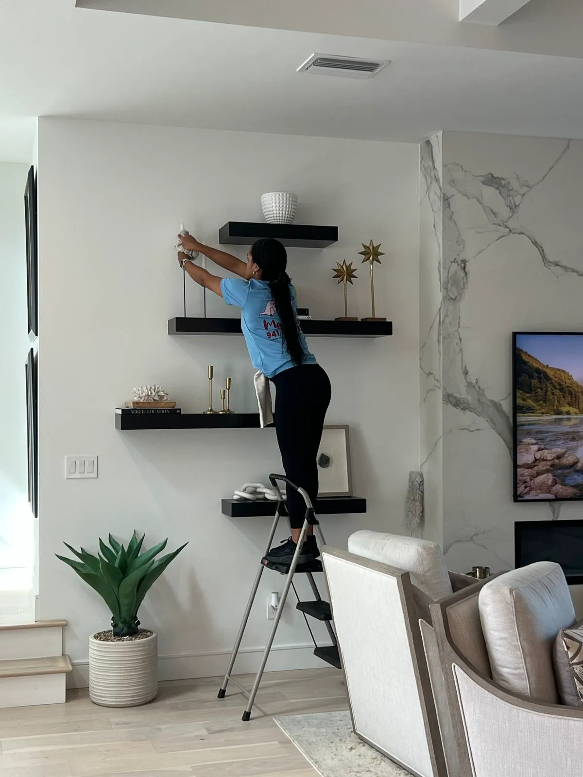 Manatee Ladies cleaner dusting floating shelves in a Sarasota living room