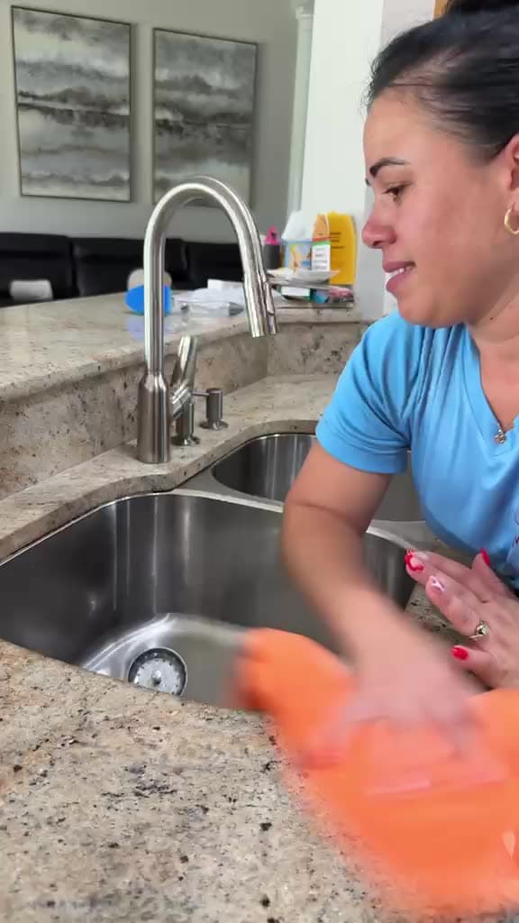 Manatee Ladies cleaner polishing a stainless steel kitchen sink in Sarasota FL